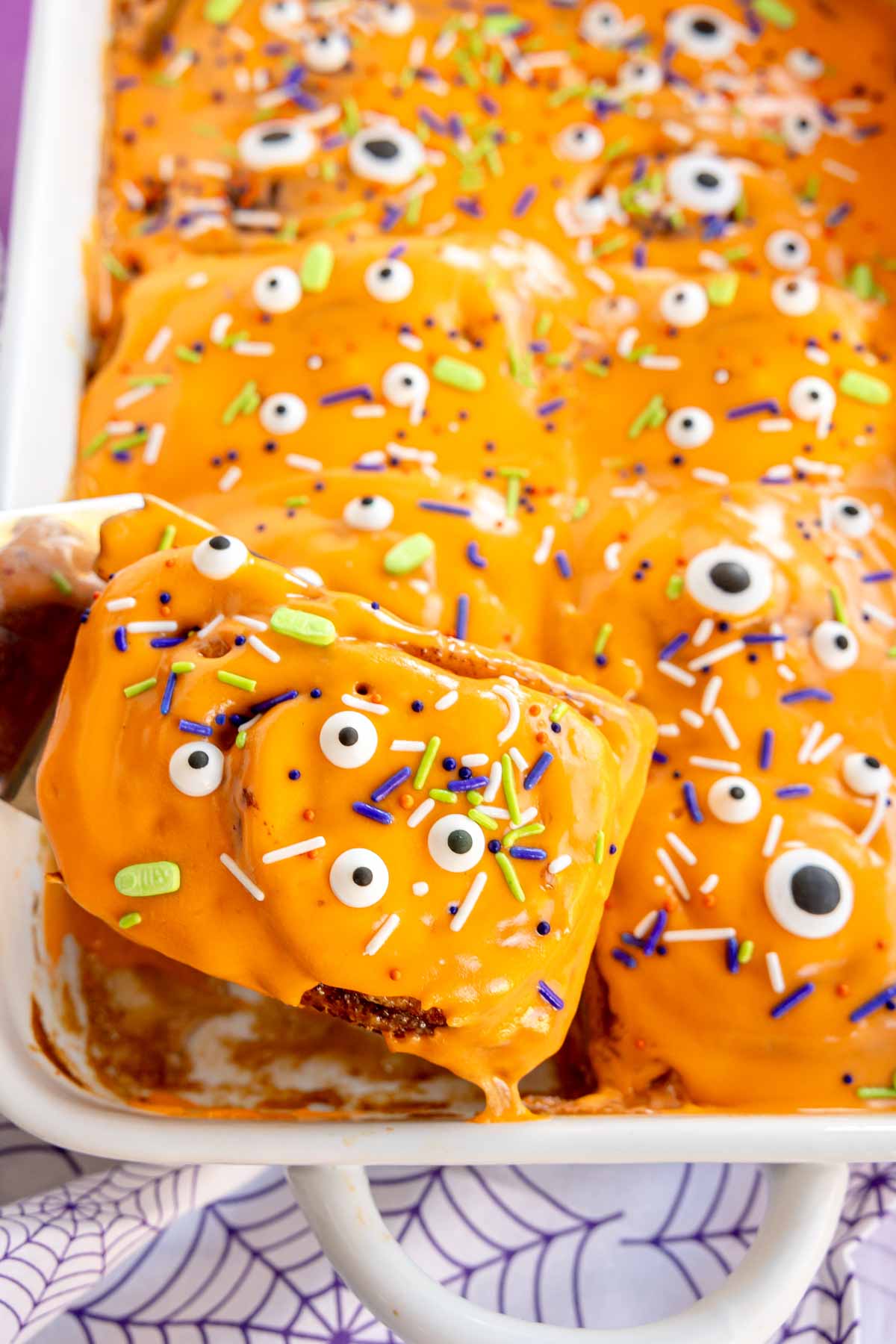 spatula pulling out a Halloween cinnamon roll from a pan