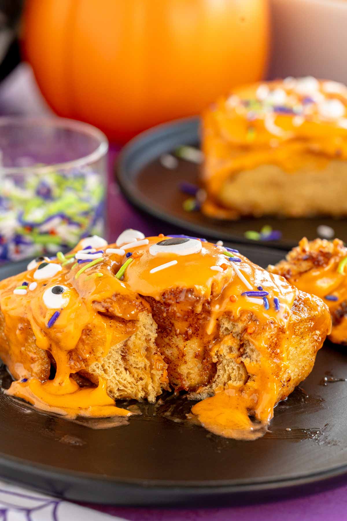 half cut Halloween cinnamon roll on a black plate