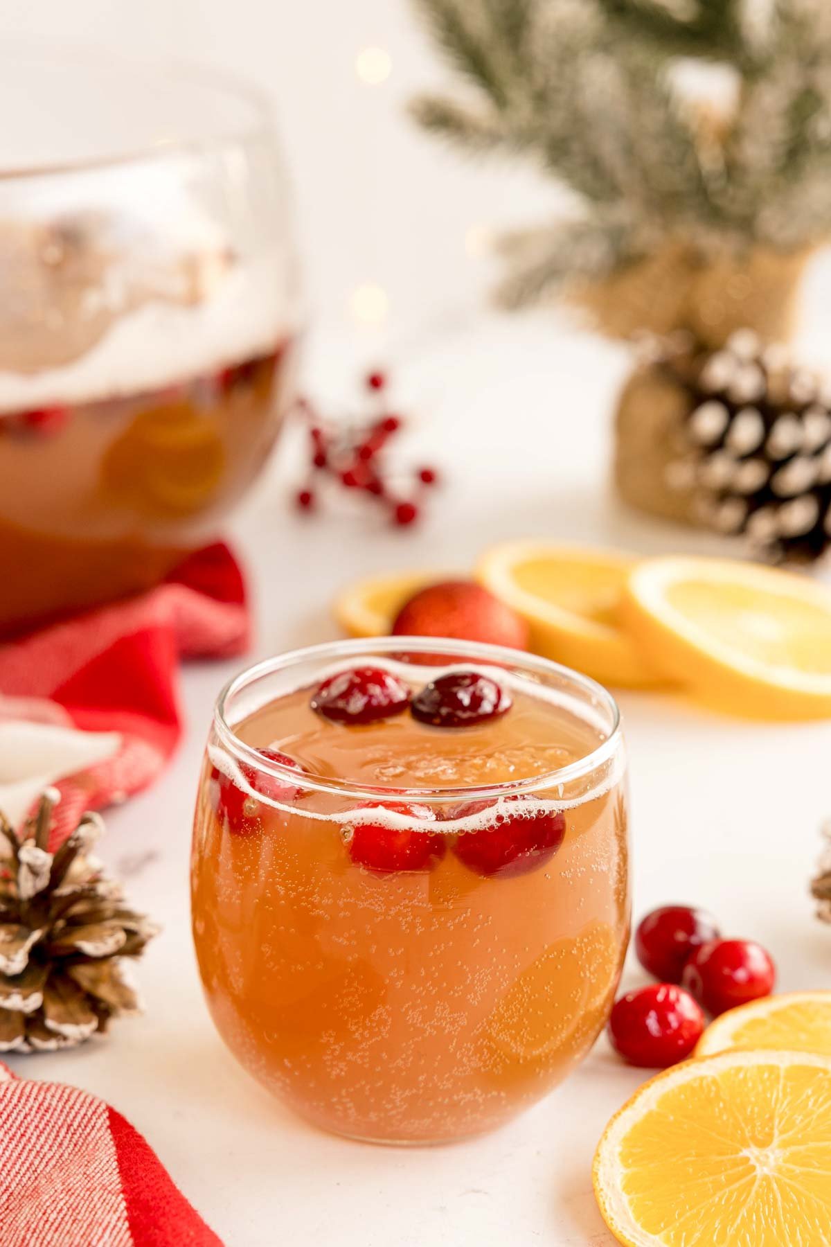 glass of Christmas punch in front of a Christmas punch bowl