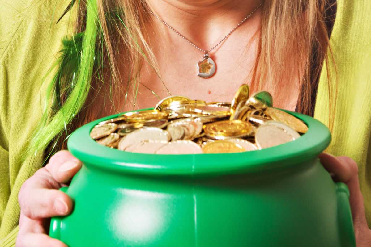 woman in a green shirt holding a green pot with gold coins