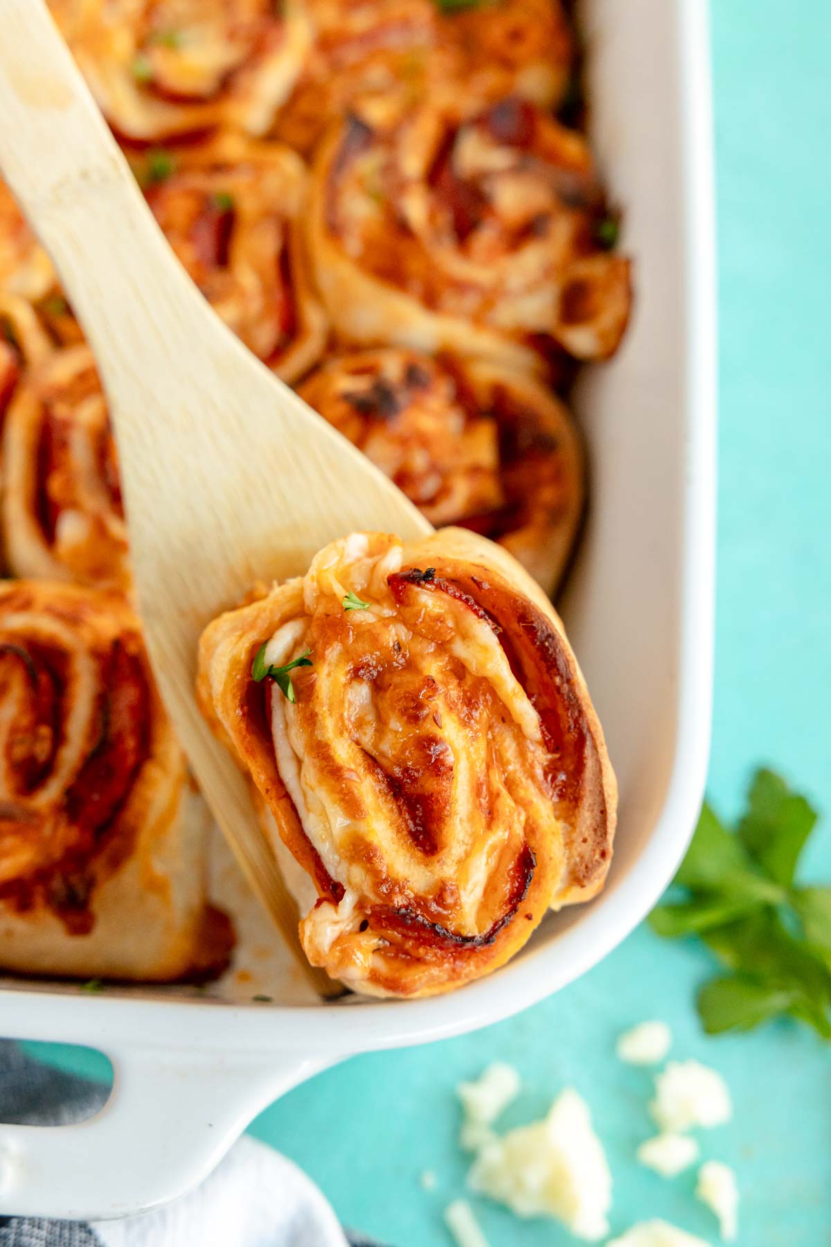 a wooden spatula underneath a pepperoni roll 