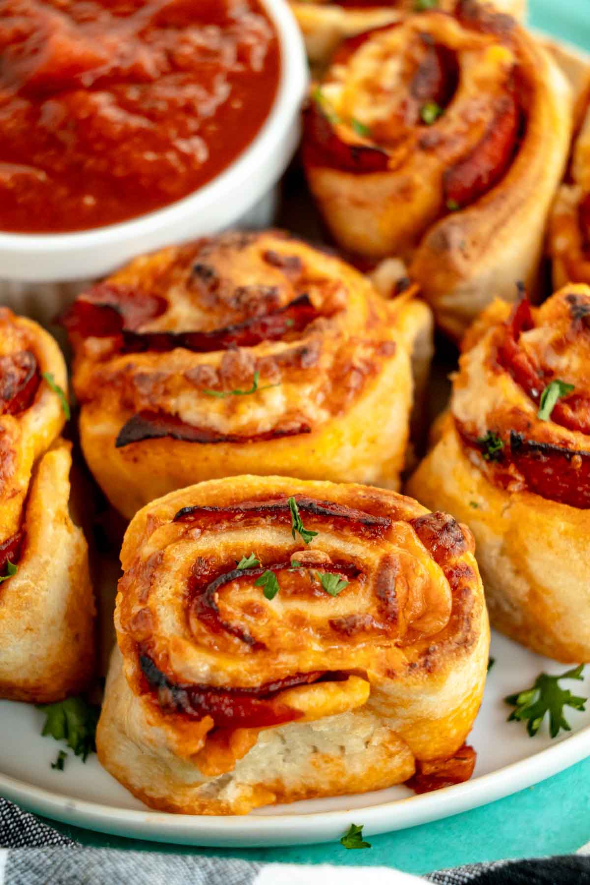 pepperoni rolls on a teal plate with pizza sauce