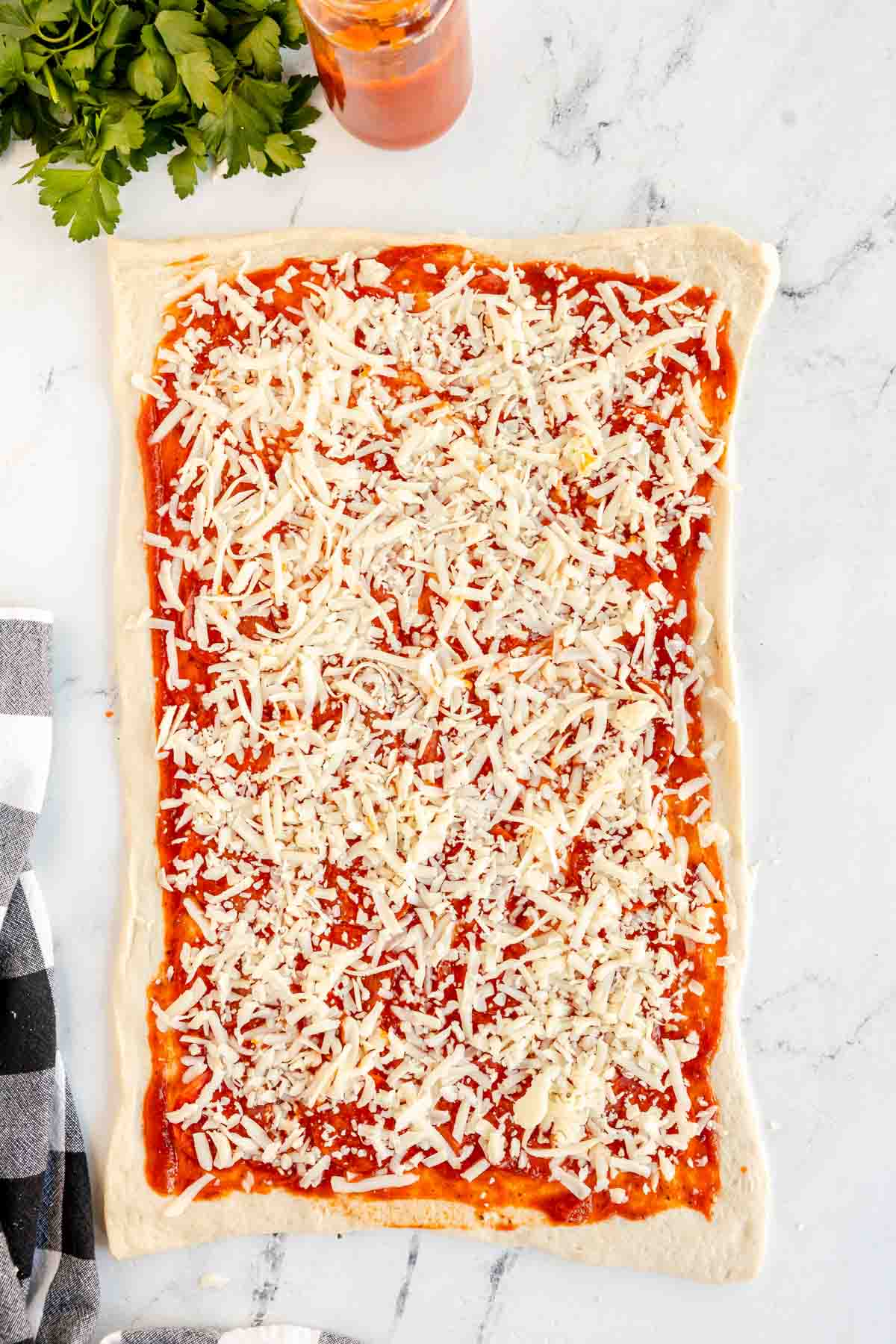 large rectangle pizza dough covered with cheese and pepperoni