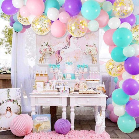 colorful balloon arch with a unicorn party table