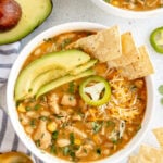 white chicken chili with avocado and tortilla chips on top