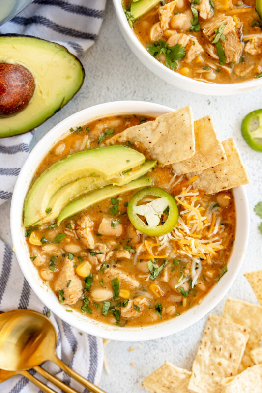 white chicken chili with avocado and tortilla chips on top