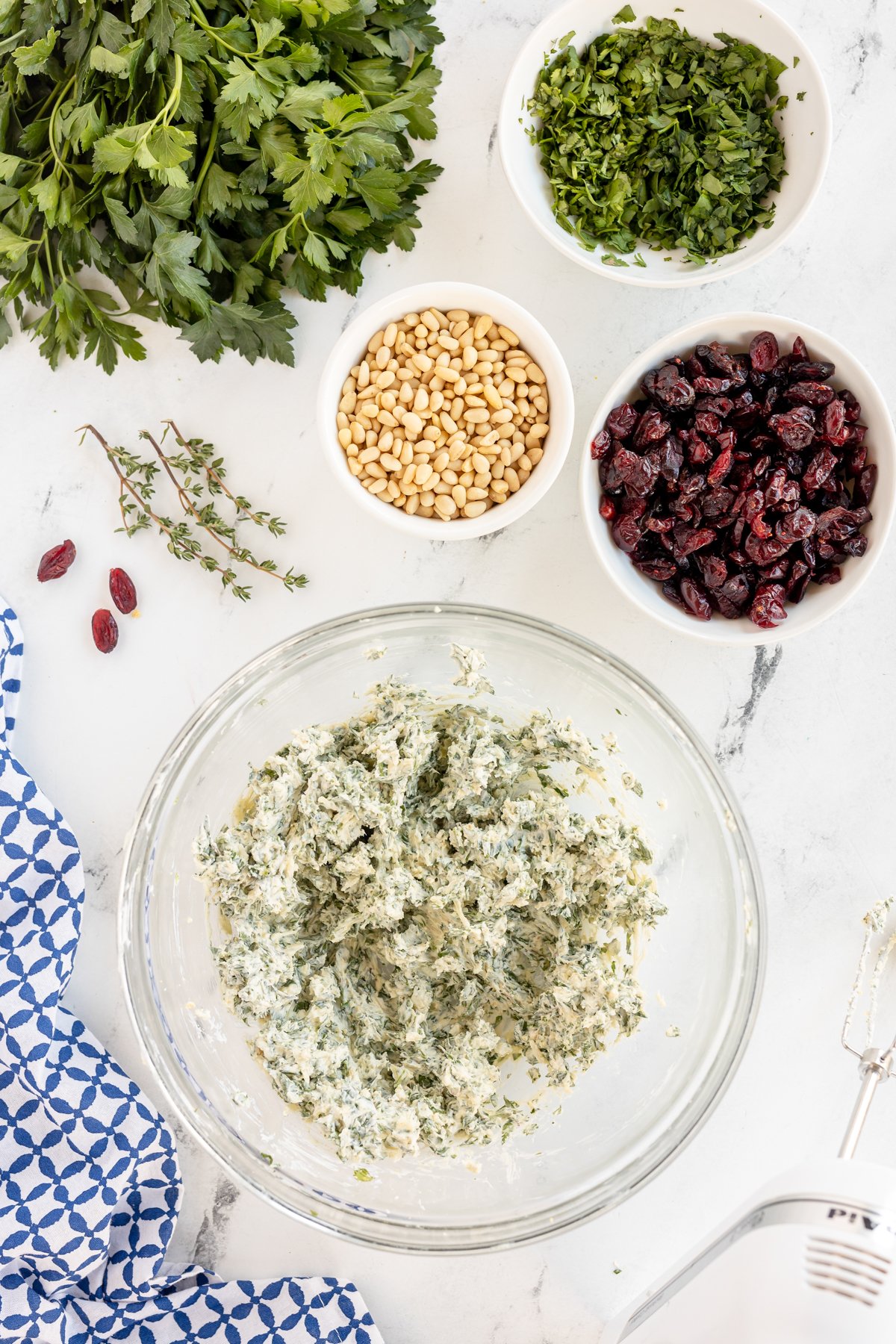 a glass bowl with a cream cheese and herb mixture