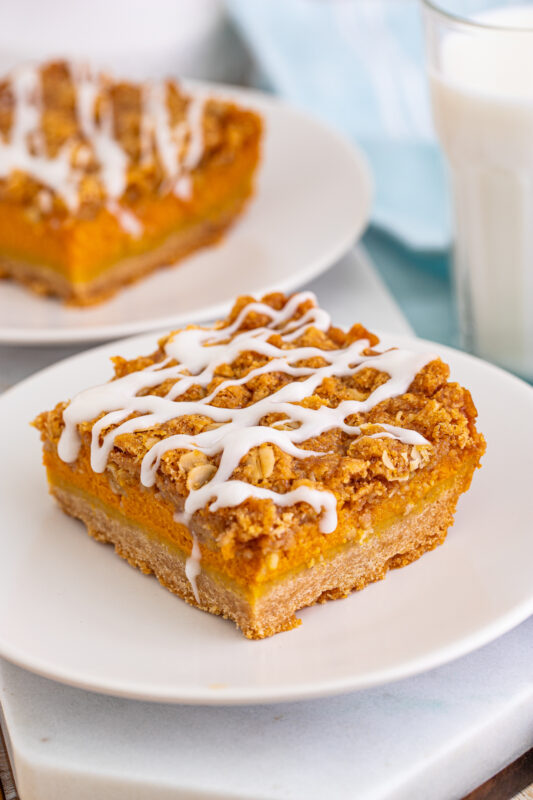 Two pumpkin streusel bars on white plates