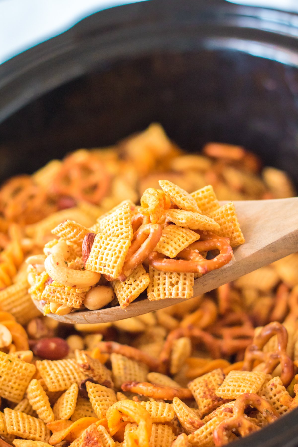 spoon full of ranch chex mix above a slow cooker