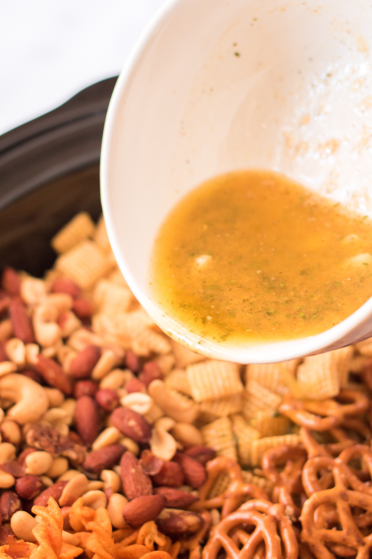 pouring seasonings on ranch chex mix in a slow cooker