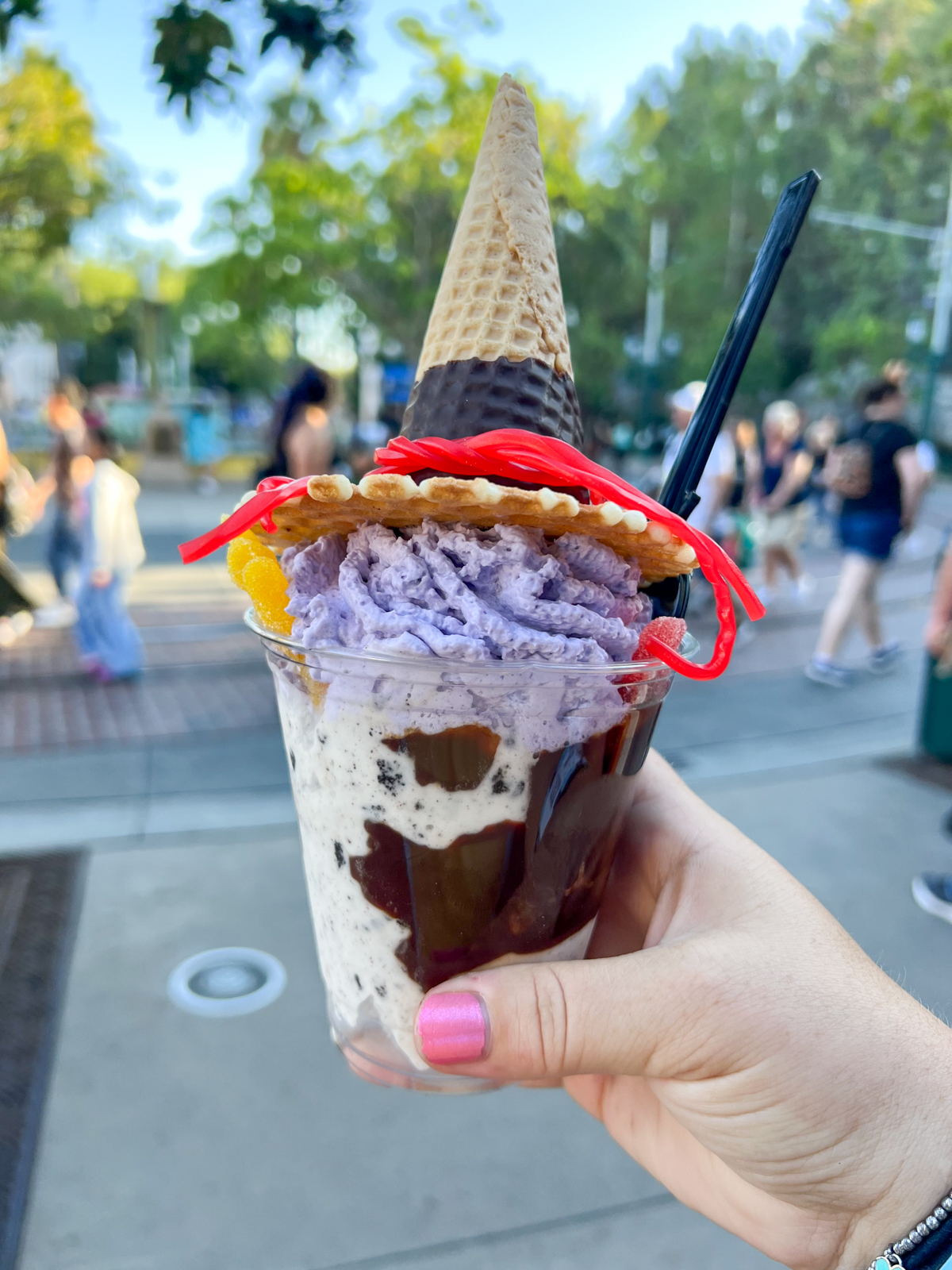 hand holding an ice cream sundae with a with hat cone