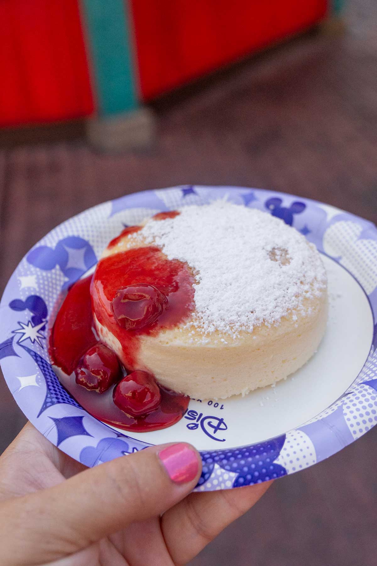 hand holding a Disneyland plate with Aunt Cass cheesecake on top