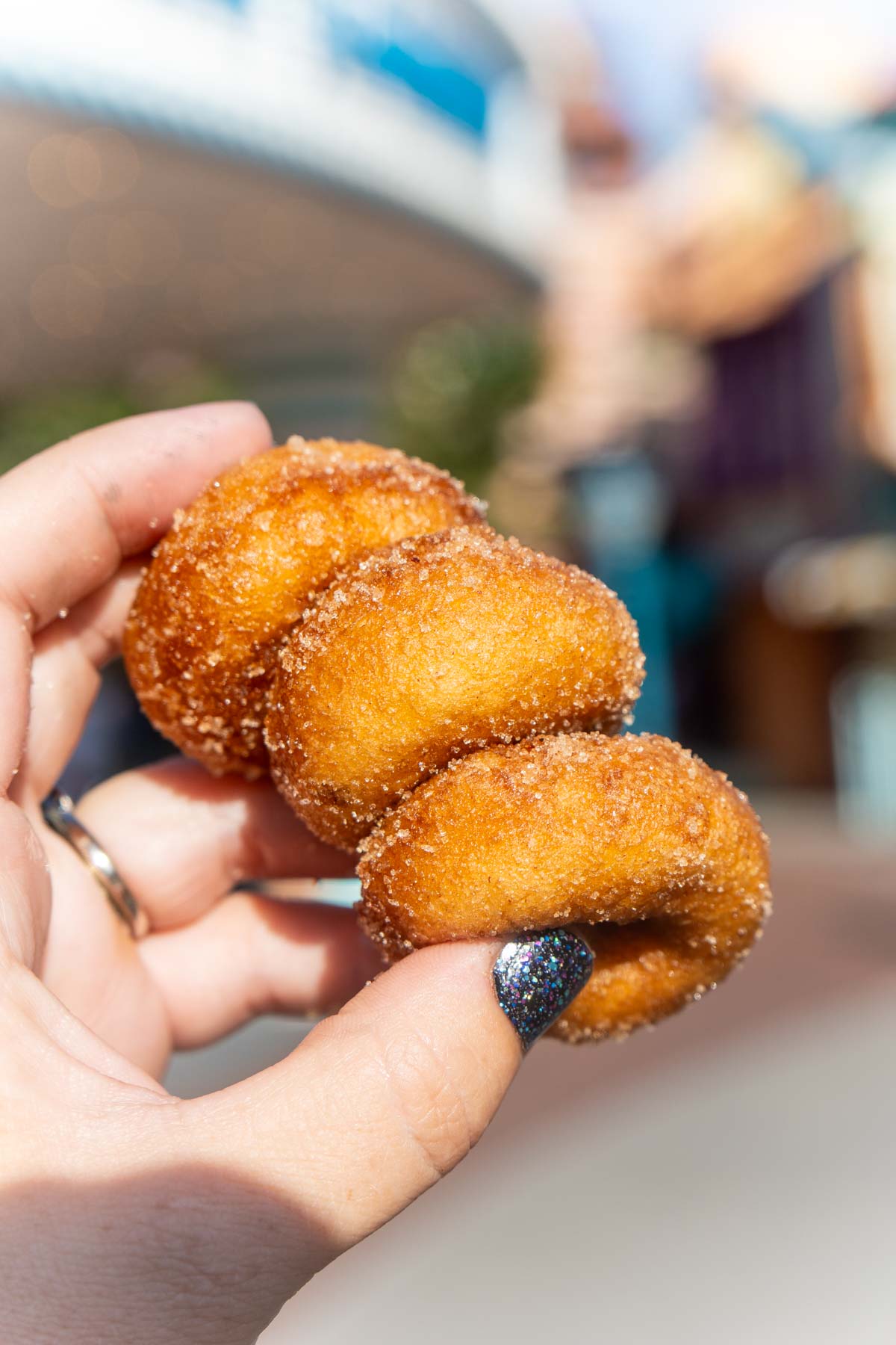 hand holding three apple cider donuts at Disneyland