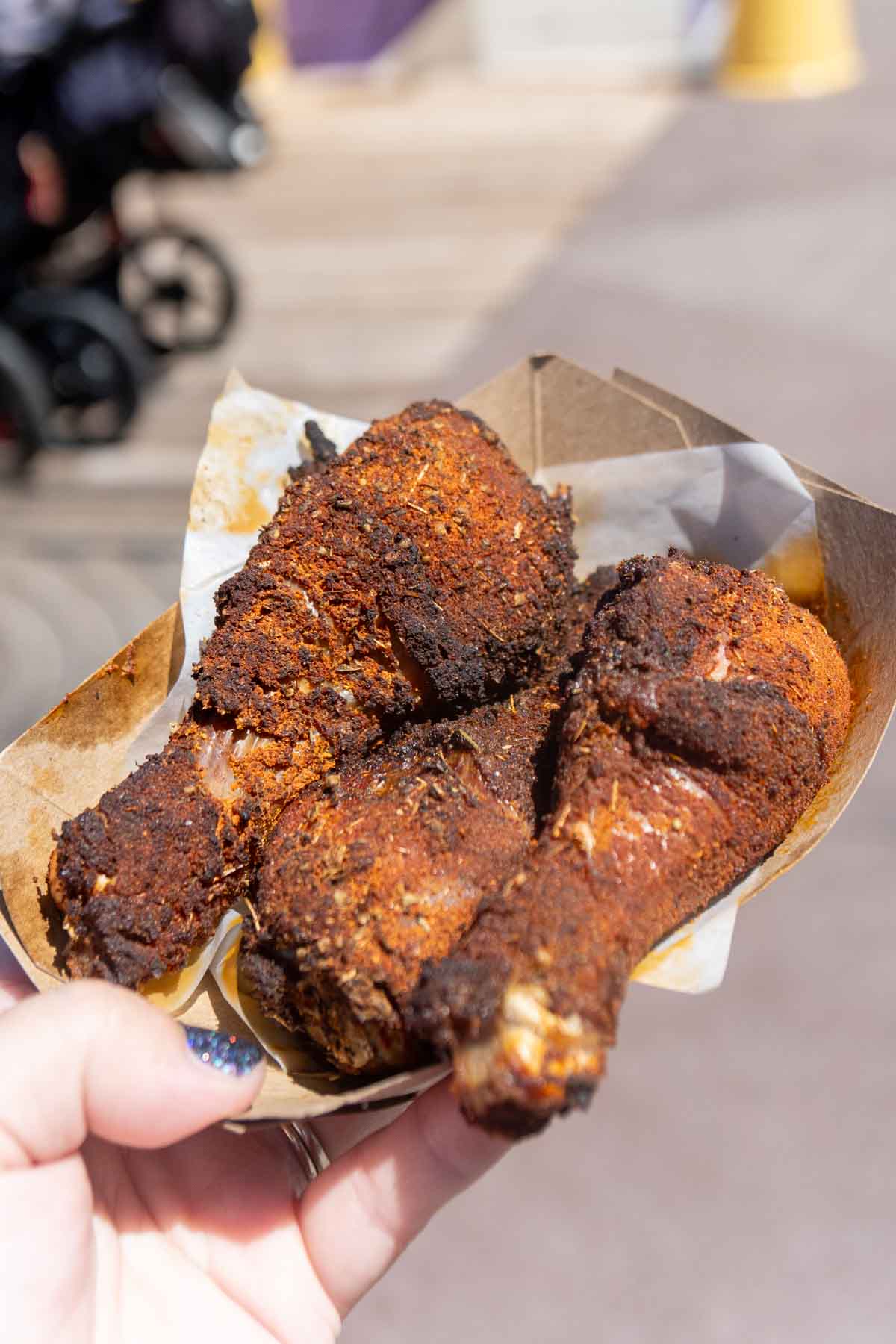 Hand holding a tray with chipotle chicken wings at Disneyland