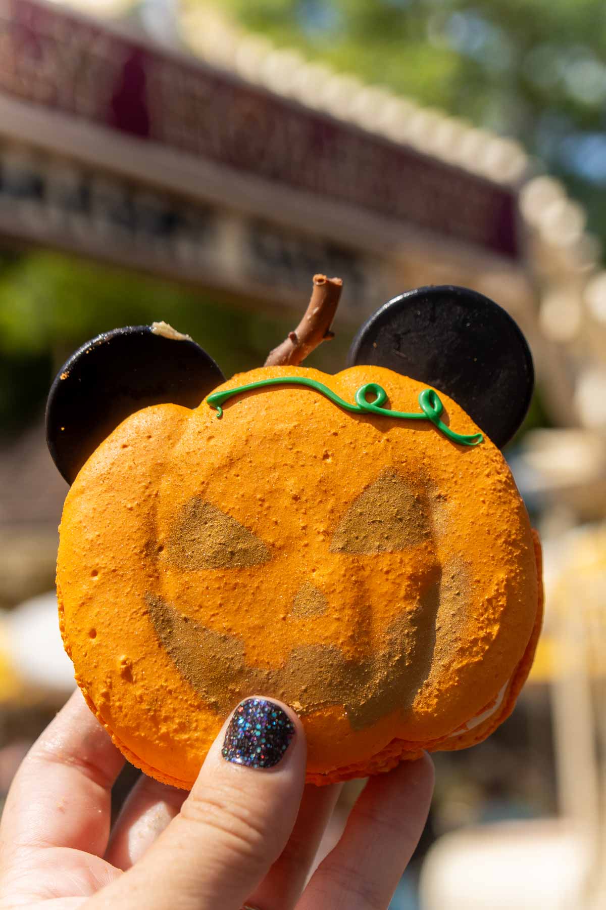 Hand holding a Mickey pumpkin macaron at Disneyland