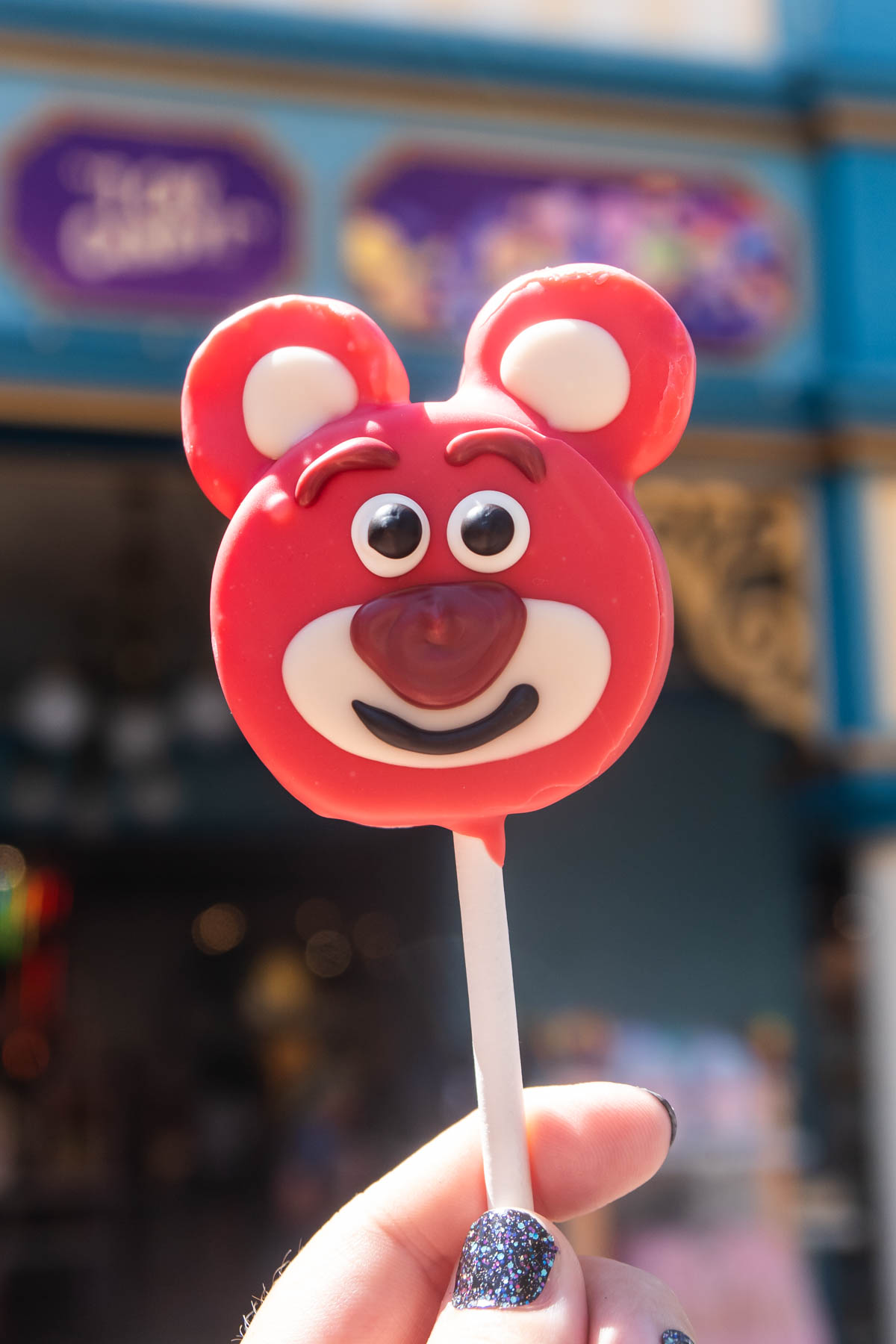 Hand holding a Lotso cake pop at Disneyland