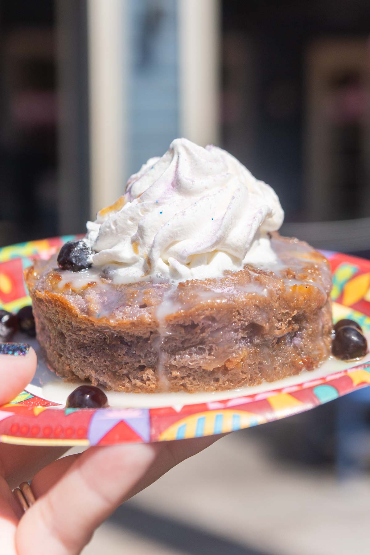 hand holding a plate with taro bread pudding from Disneyland