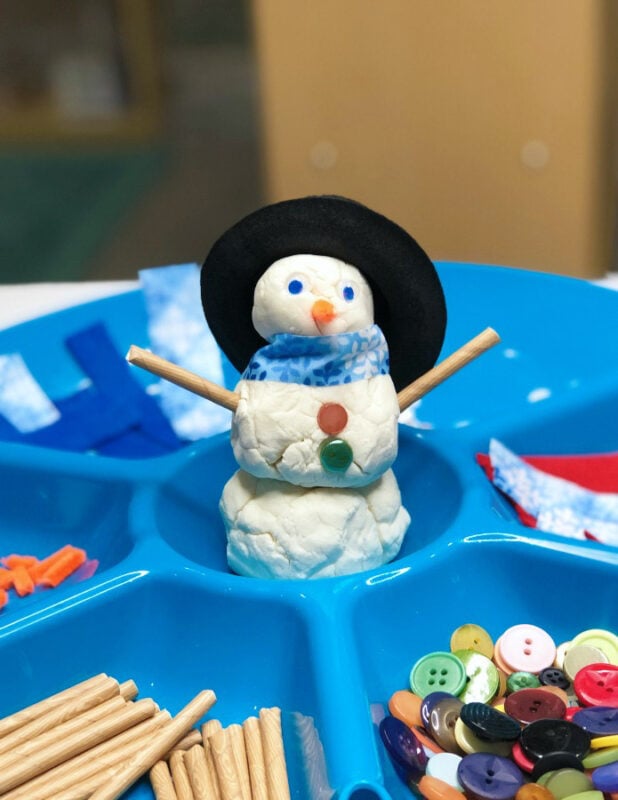 playdough snowman with decorating items in tray around it