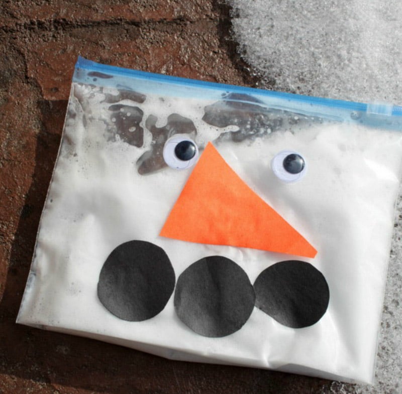 ziplock bag decorated with snowman face items and filled with white liquid.