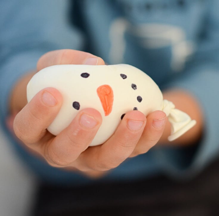 white balloon filled with flour to make a stress ball with a snowman face drawn on