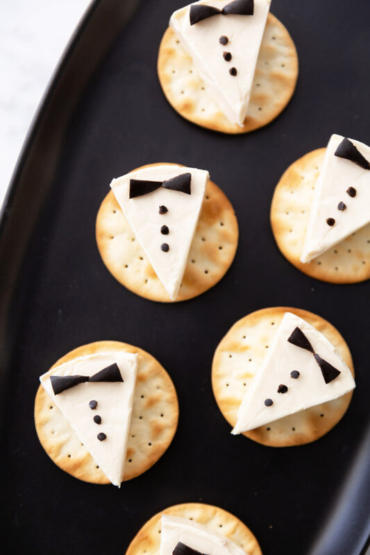 Cheese triangles on crackers made to look like little tuxedos