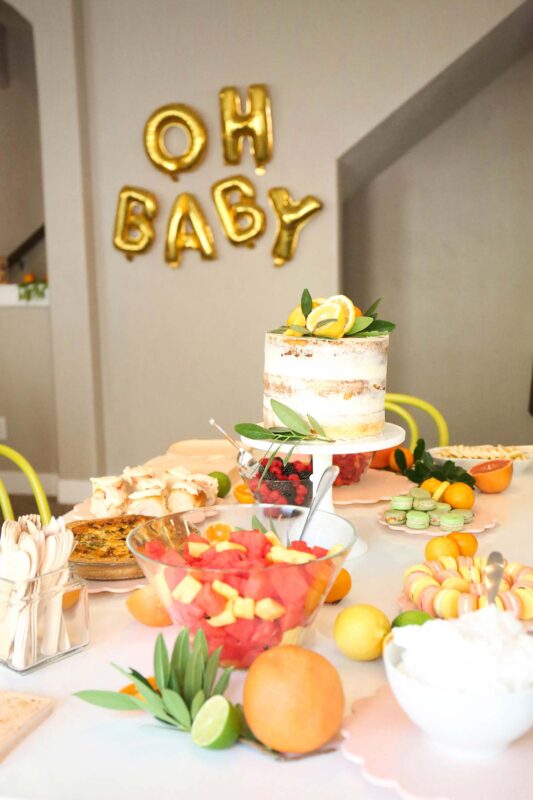 variety of food items on a table with citrus coloring and balloon letters