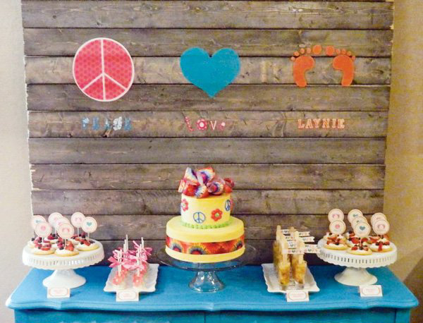 table setting with brightly colored cake and peace love baby sign