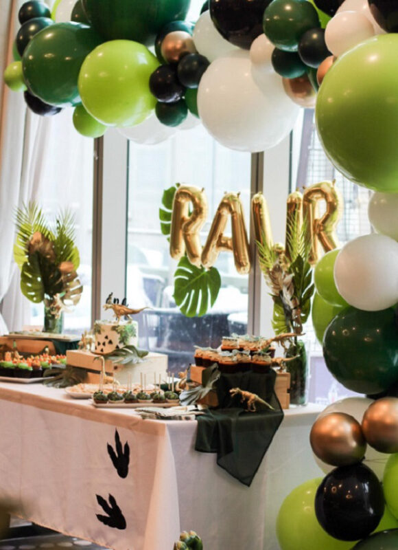 greenery on a white table with golf lettered balloons and dinosaur accents