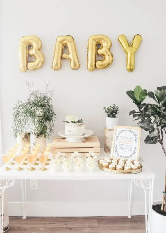 gold balloons with white and gold food on a table