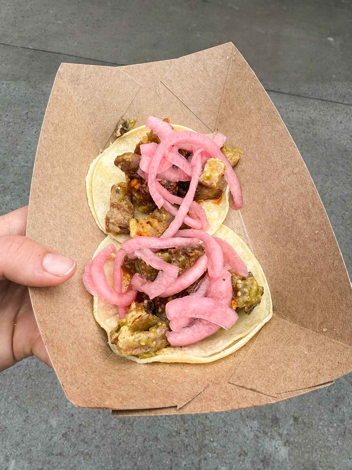 hand holding salsas verde tacos on a plate