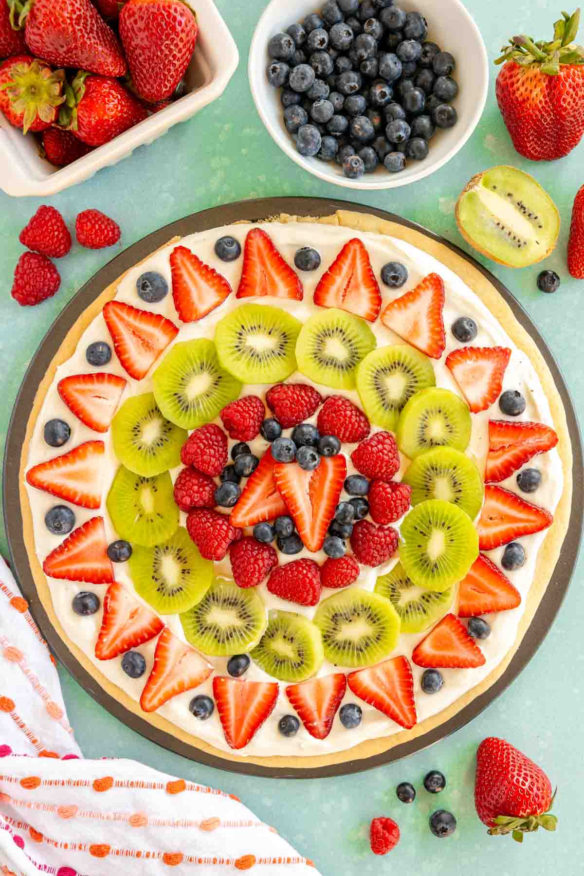 sugar cookie fruit pizza topped with all sorts of fruit