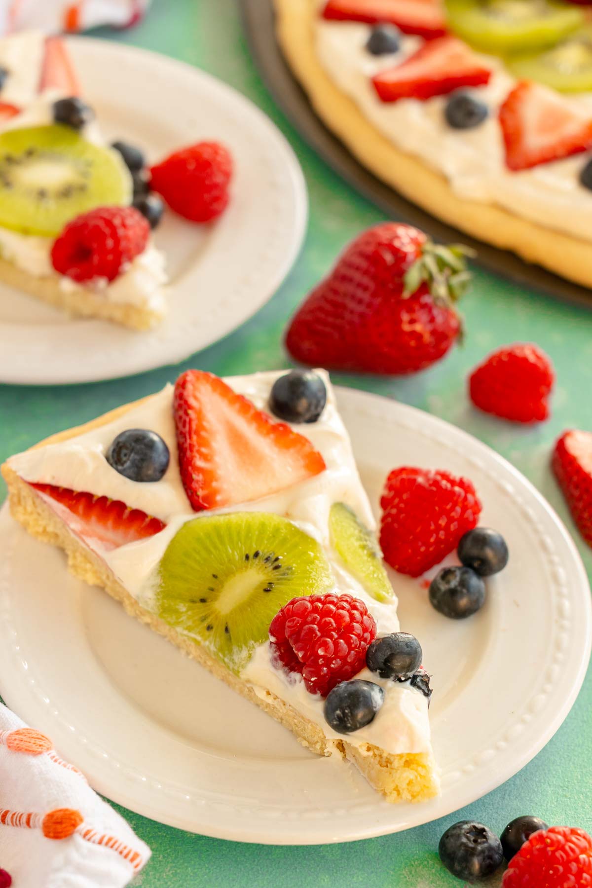 slice of sugar cookie fruit pizza on a white plate