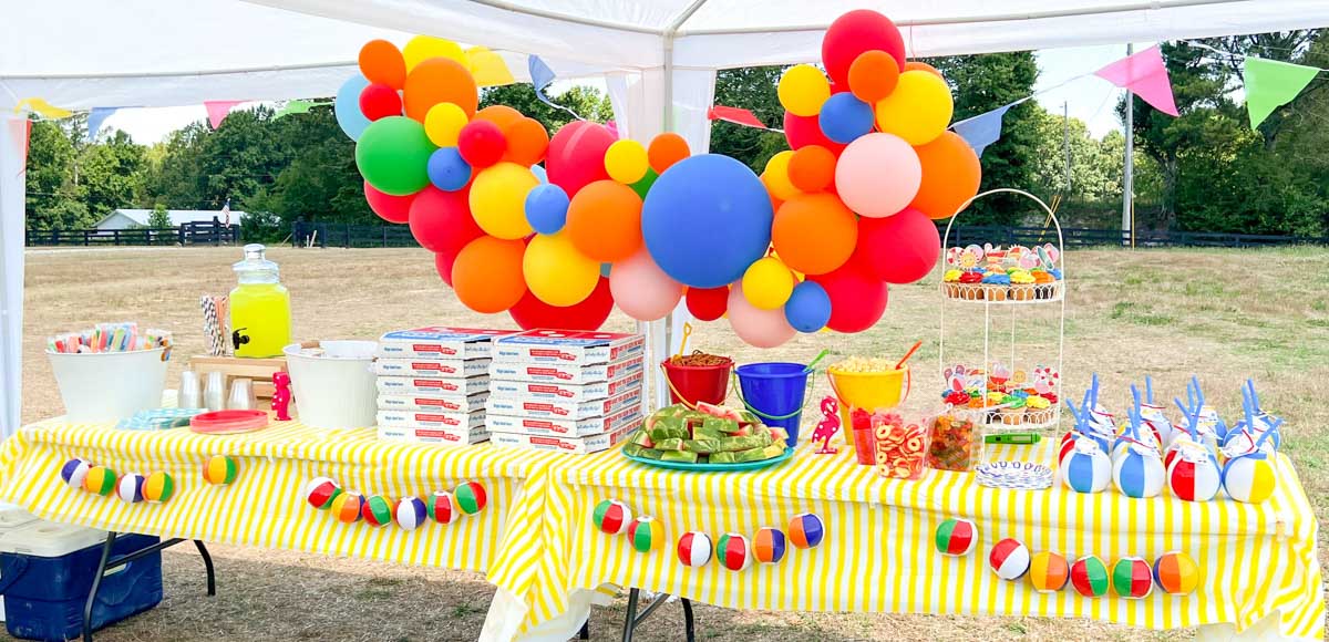 colorful balloon arch with summer-themed food table