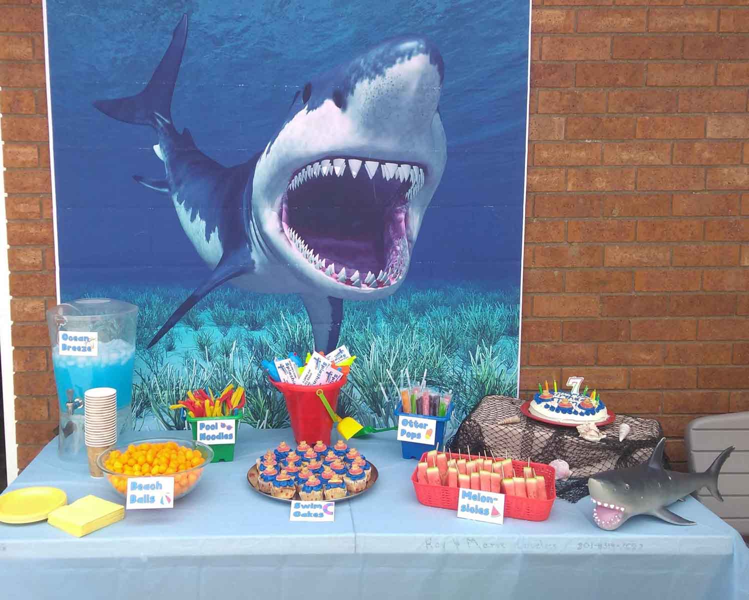 big shark poster in front of a pool party table