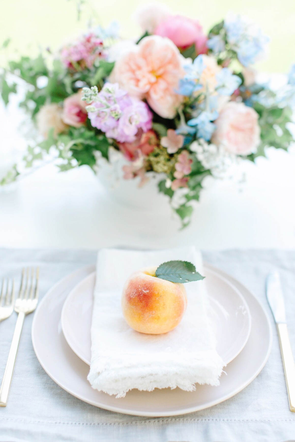a peach on a plate with flowers in the background