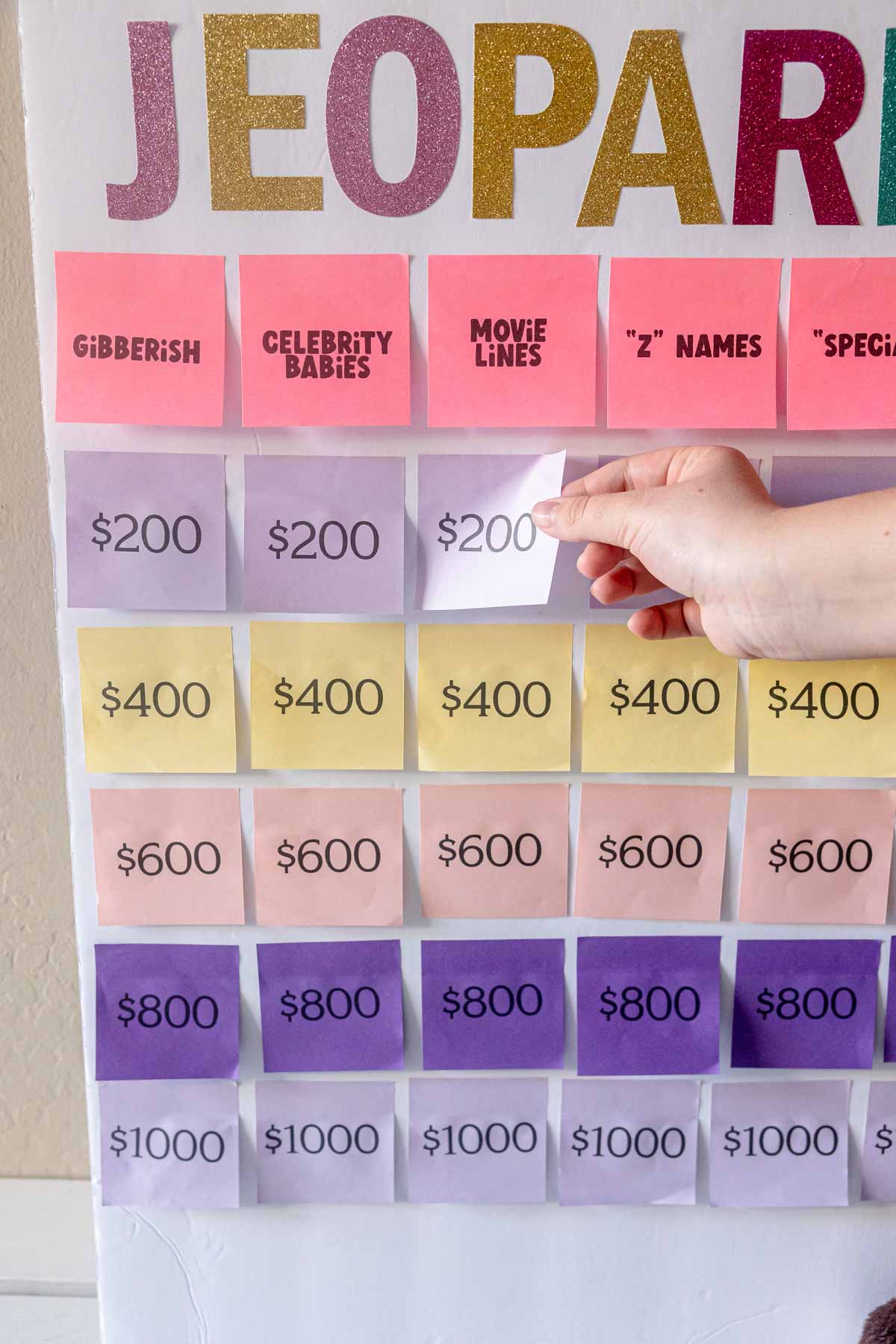 hand pulling a post-it note off a baby shower jeopardy board