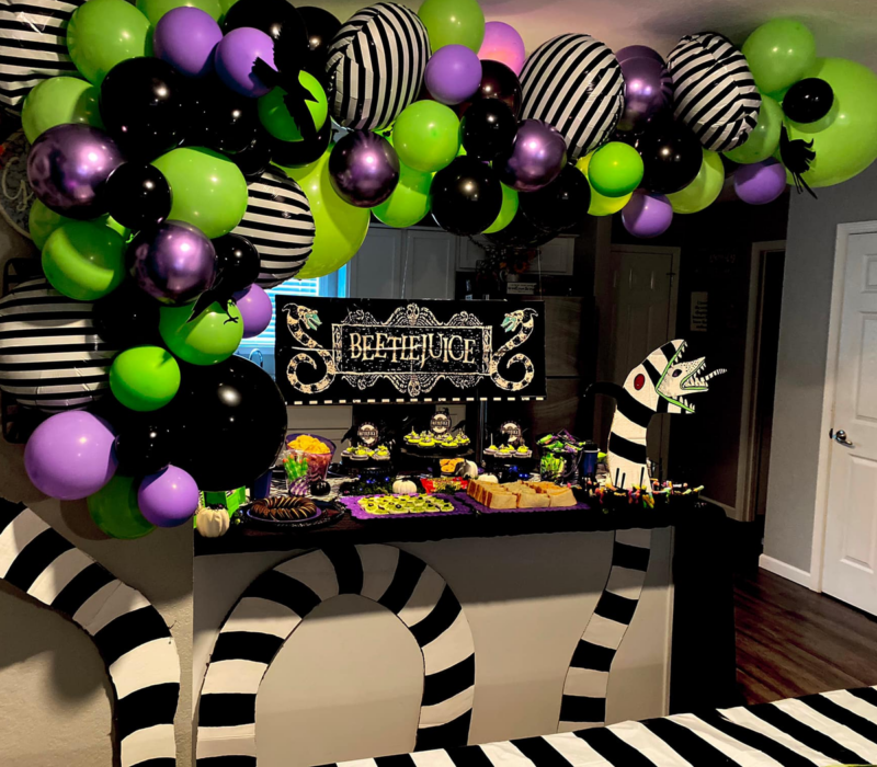 Beetlejuice party table with a balloon garland