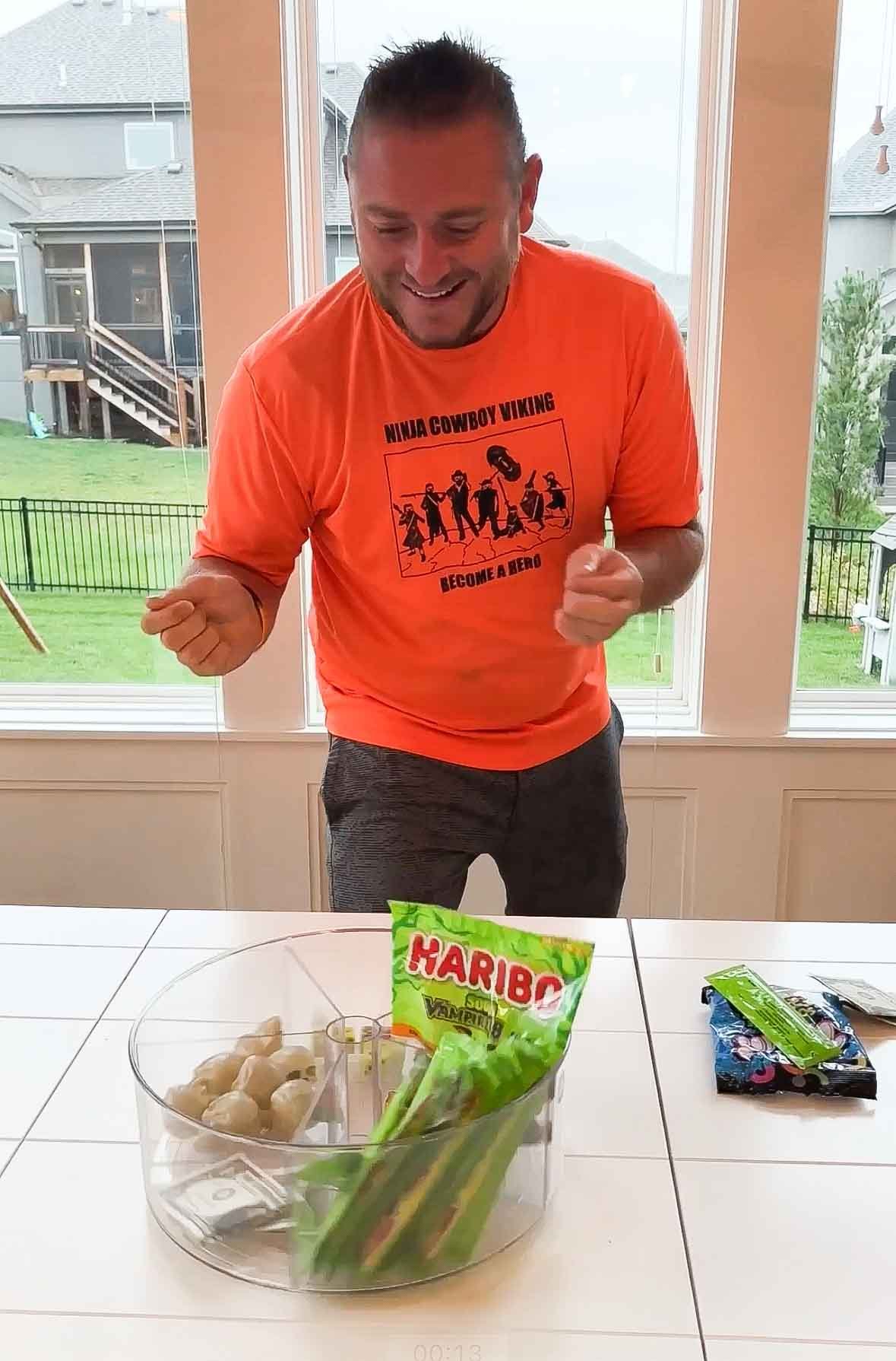 man standing behind a lazy susan filled with prizes