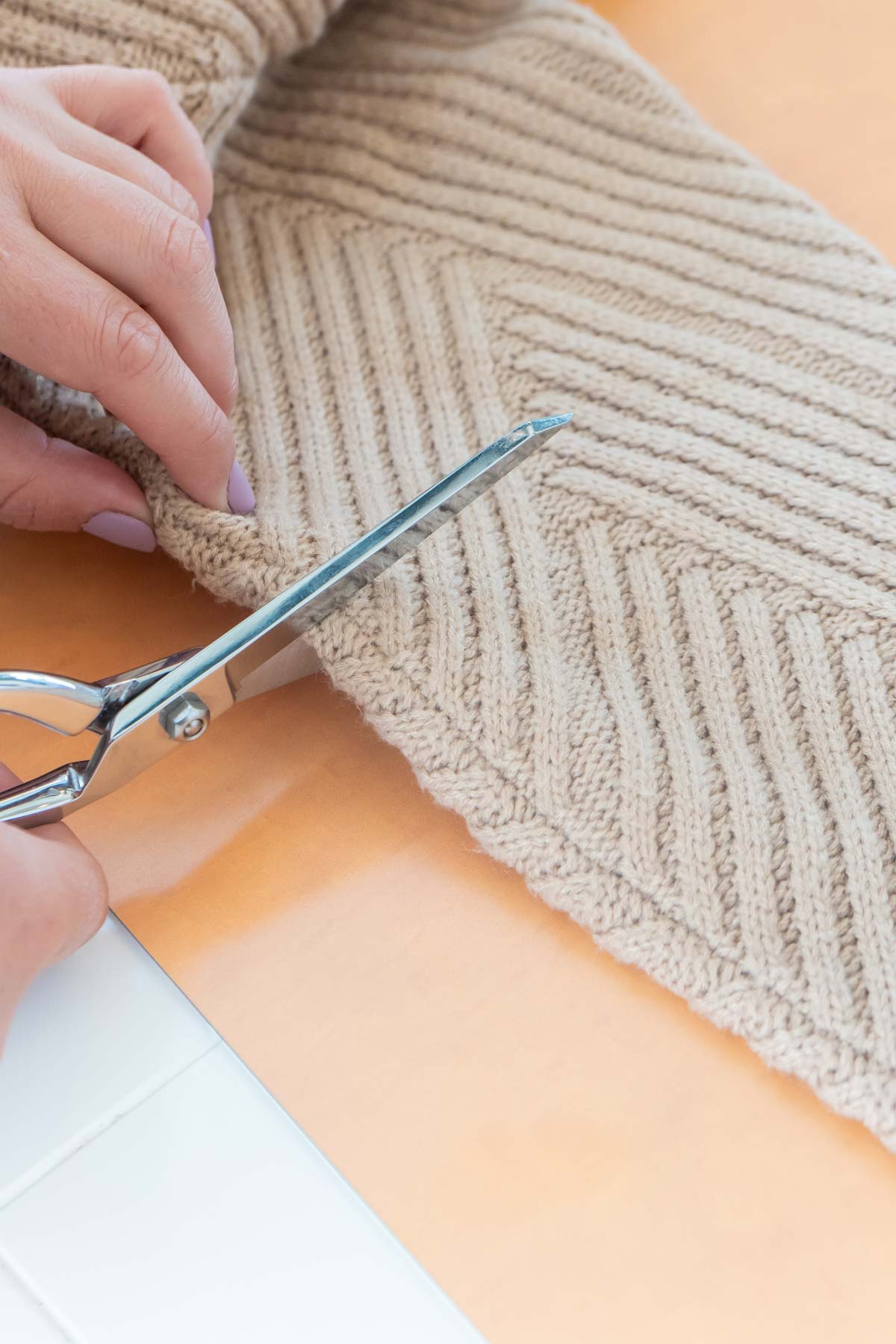 someone cutting a sweater with fabric scissors