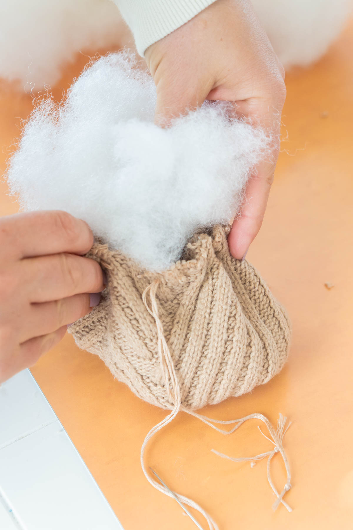 person stuffing a sweater pumpkin with stuffing