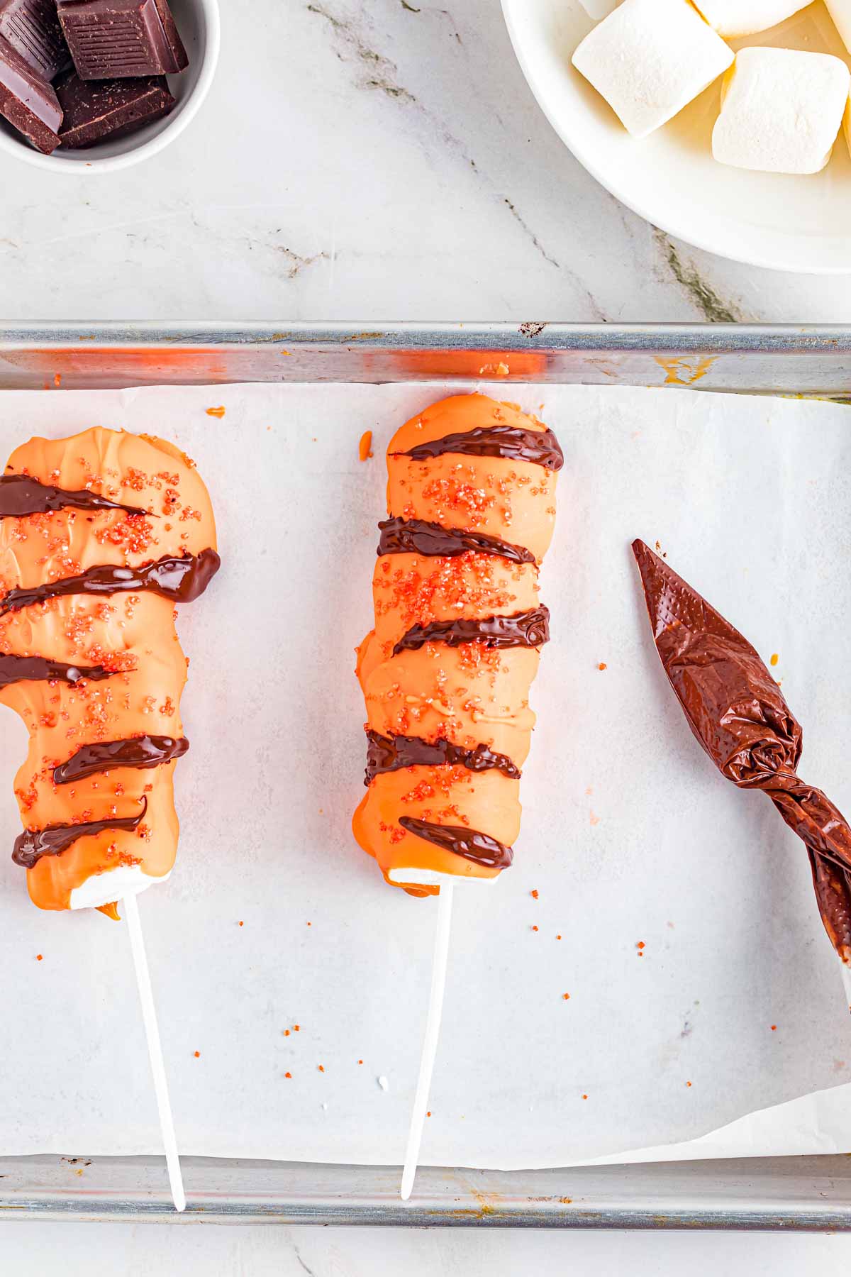 chocolate in a piping bag next to Tigger Tails on a baking sheet