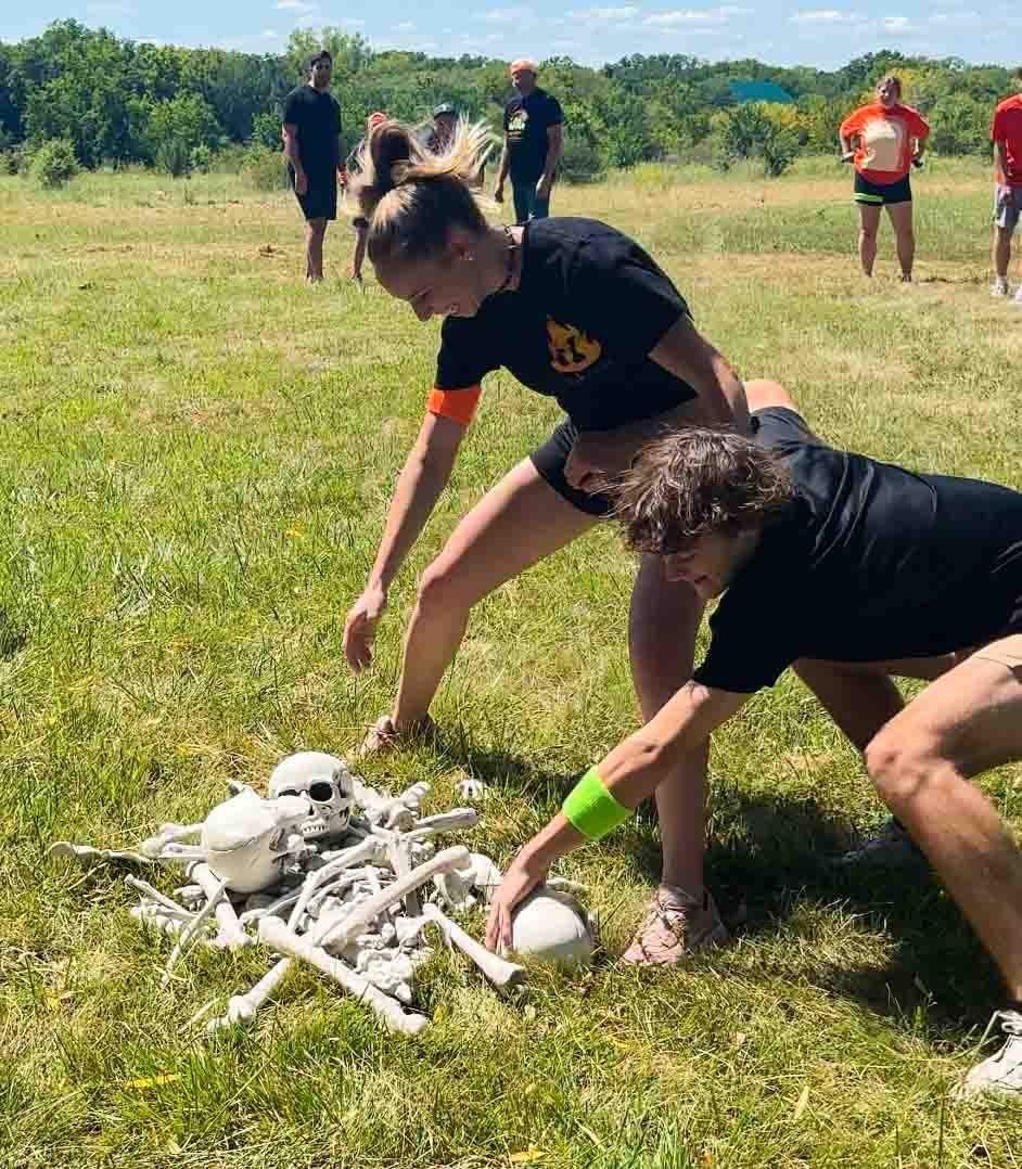 two adults grabbing bones out of a pile of bones