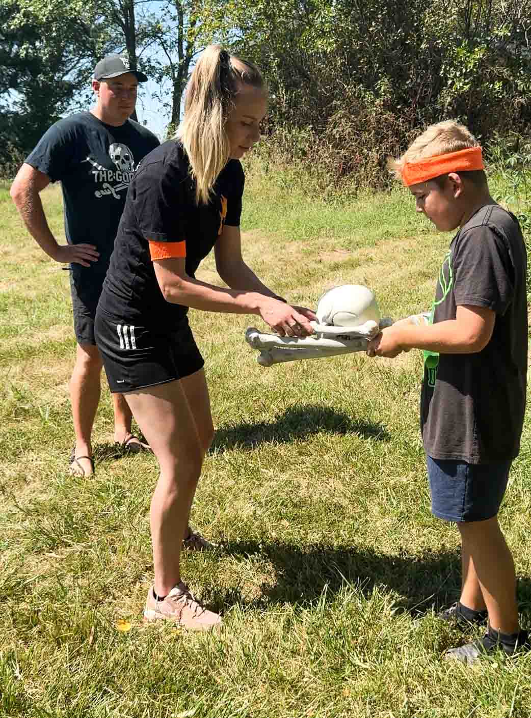 a kid passing a skull to an adult on bones