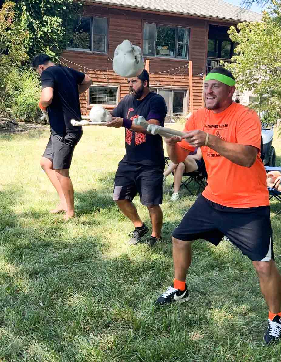 three men trying to catch a skull on bones