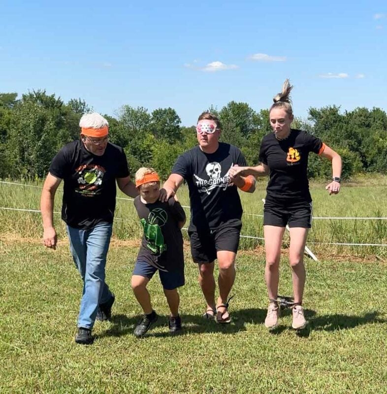 four adults jumping along an obstacle course