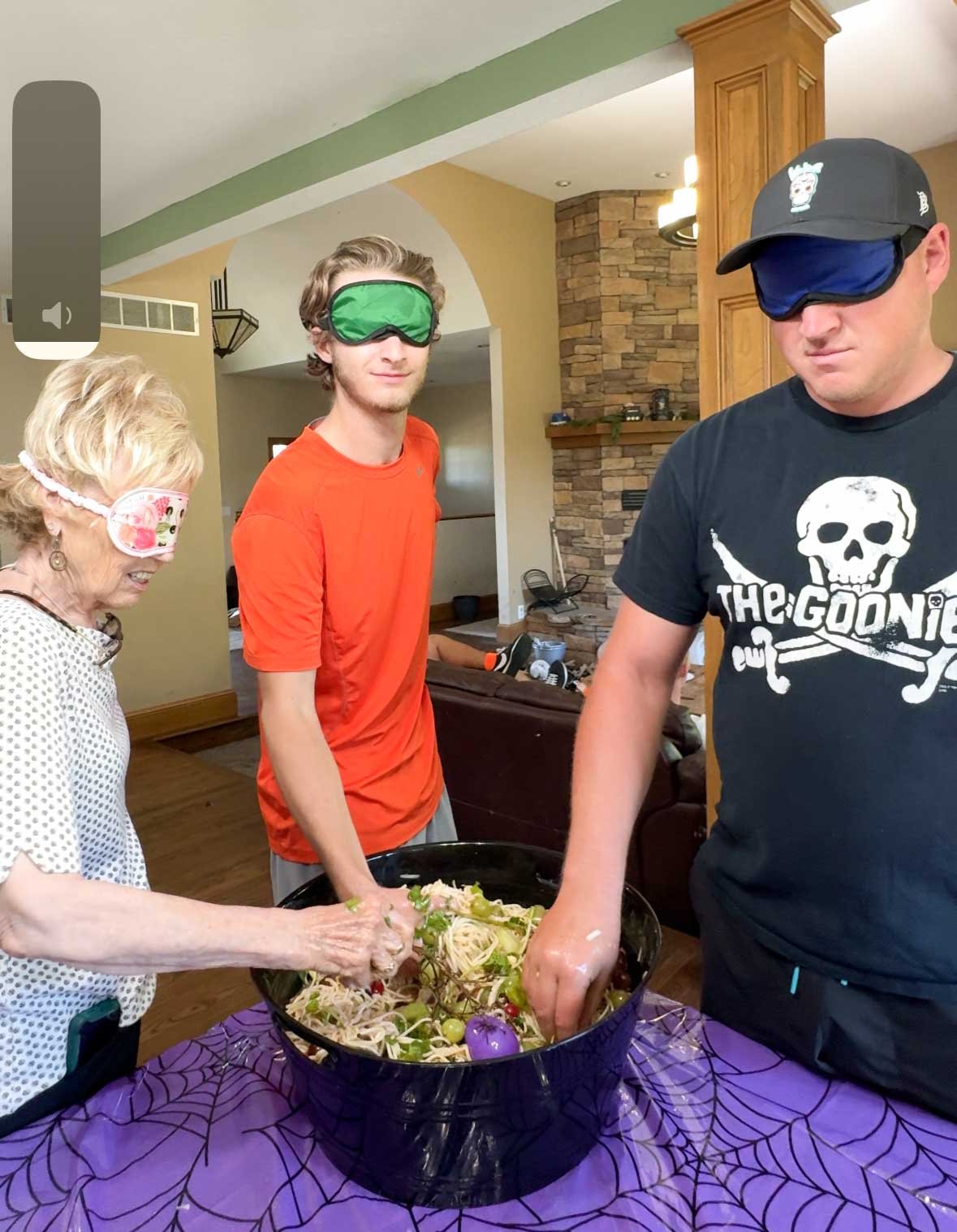 three adults with their hands in a witch's brew cauldron 