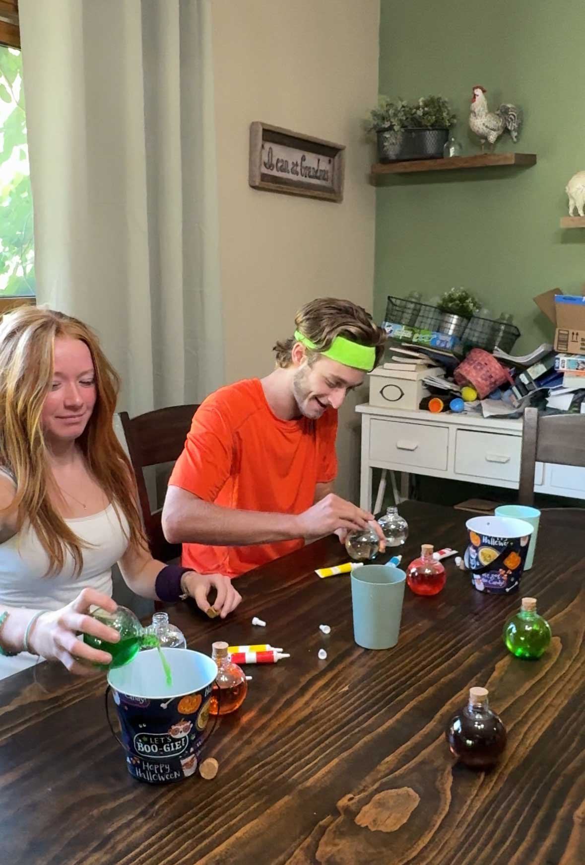 kids sitting at a table making colored water potions 