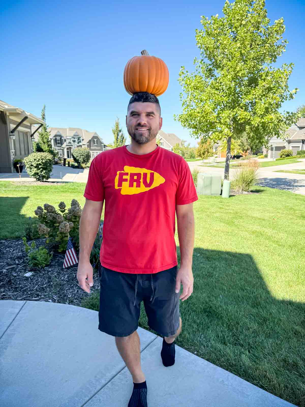 man standing on a sidewalk with a pumpkin