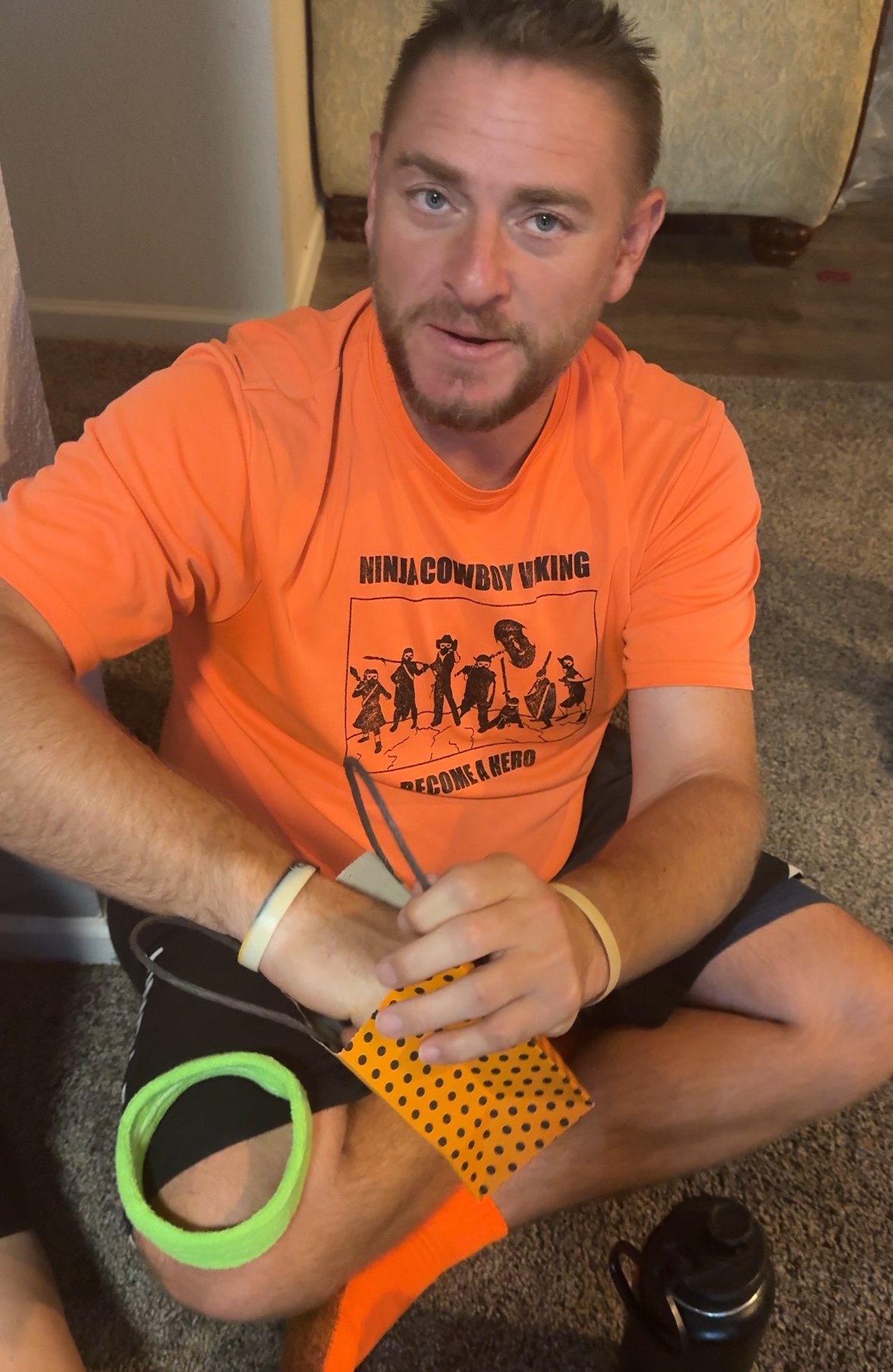 man in an orange shirt pulling a piece of paper out of a Halloween bag