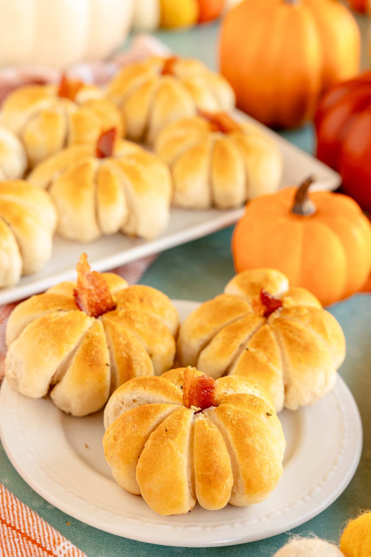 a bunch of pumpkin shaped rolls on a white plate